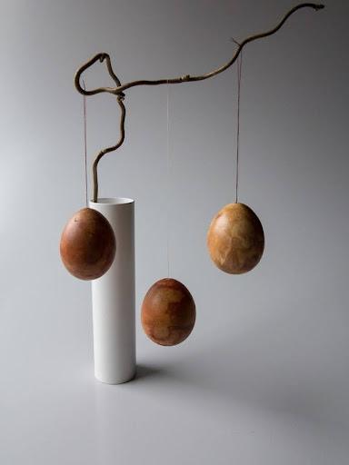 Dekorative påskeæg DIY - hænger fra grene i en elegant vase, minimalistisk på en neutral baggrund.