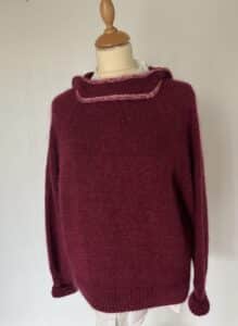 Overdimensioneret bordeauxrød strikket hoodie sweater med kjoleform, en hyggelig, blød tekstur og en diskret lyserød kravedetalje.