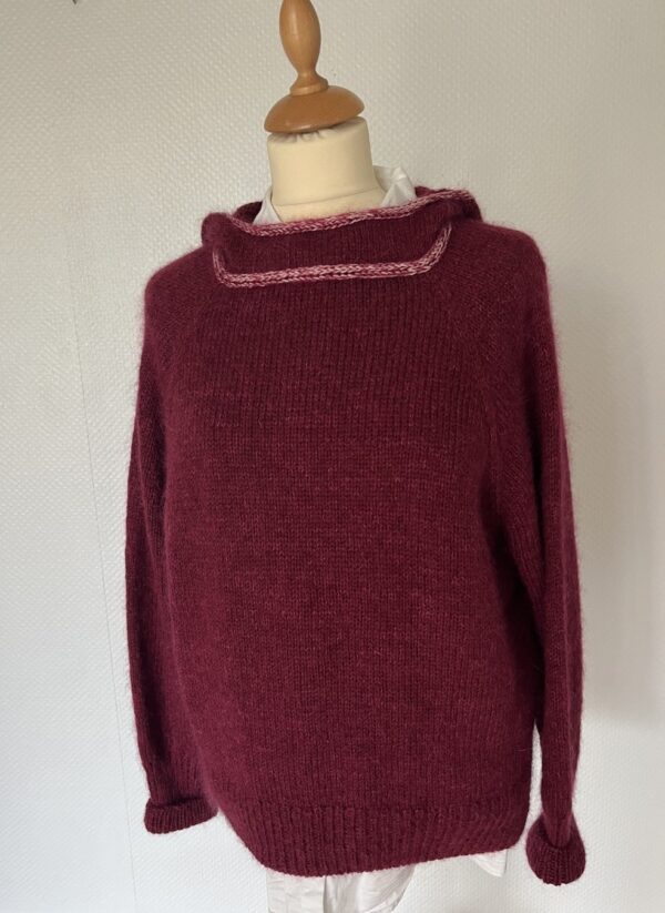 Oversized burgundy knitted hoodie sweater with a dress shape, a cozy, soft texture and a subtle pink collar detail.