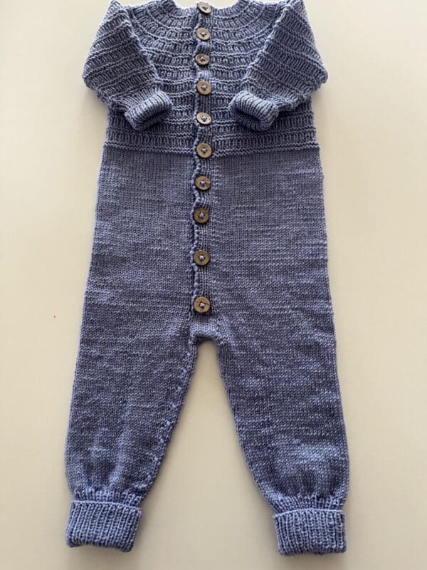 Strikket heldragt til baby. En hyggelig lyseblå strikket baby. Jumpsuit med knaplukning foran og ribkant ved ærmerne.